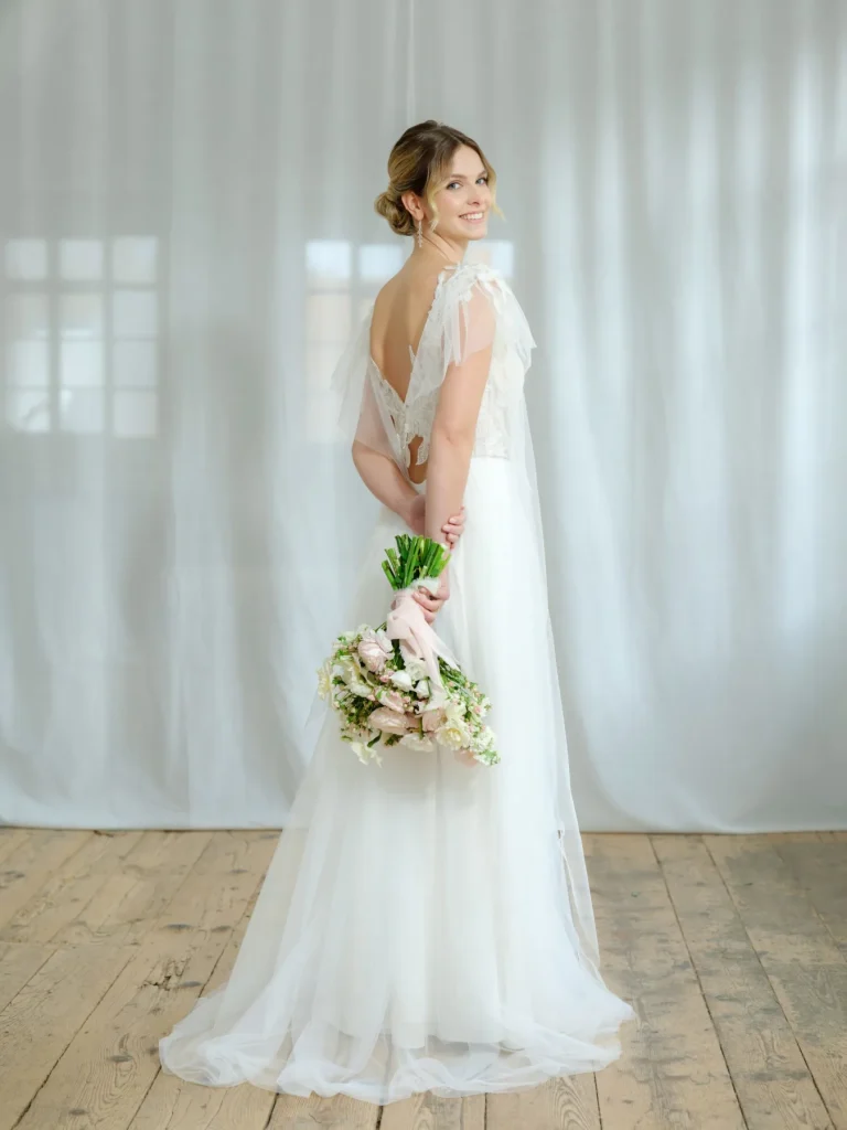 Braut im Boho-Brautkleid mit Tüllärmeln und Brautstrauß